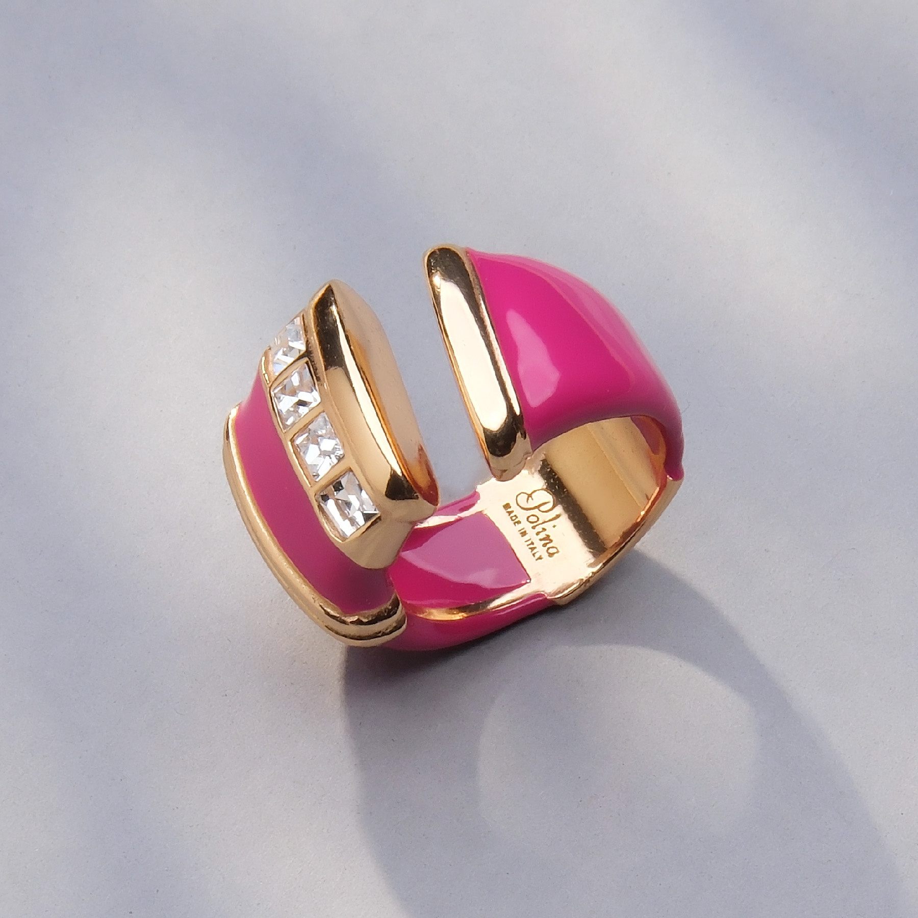 Otwarty pozłacany pierścień z różową emalią i cyrkoniami. DARIA