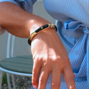 Sztywna złocona bransoletka z czarną połyskującą gumą. MIGOTLIWY WIECZÓR